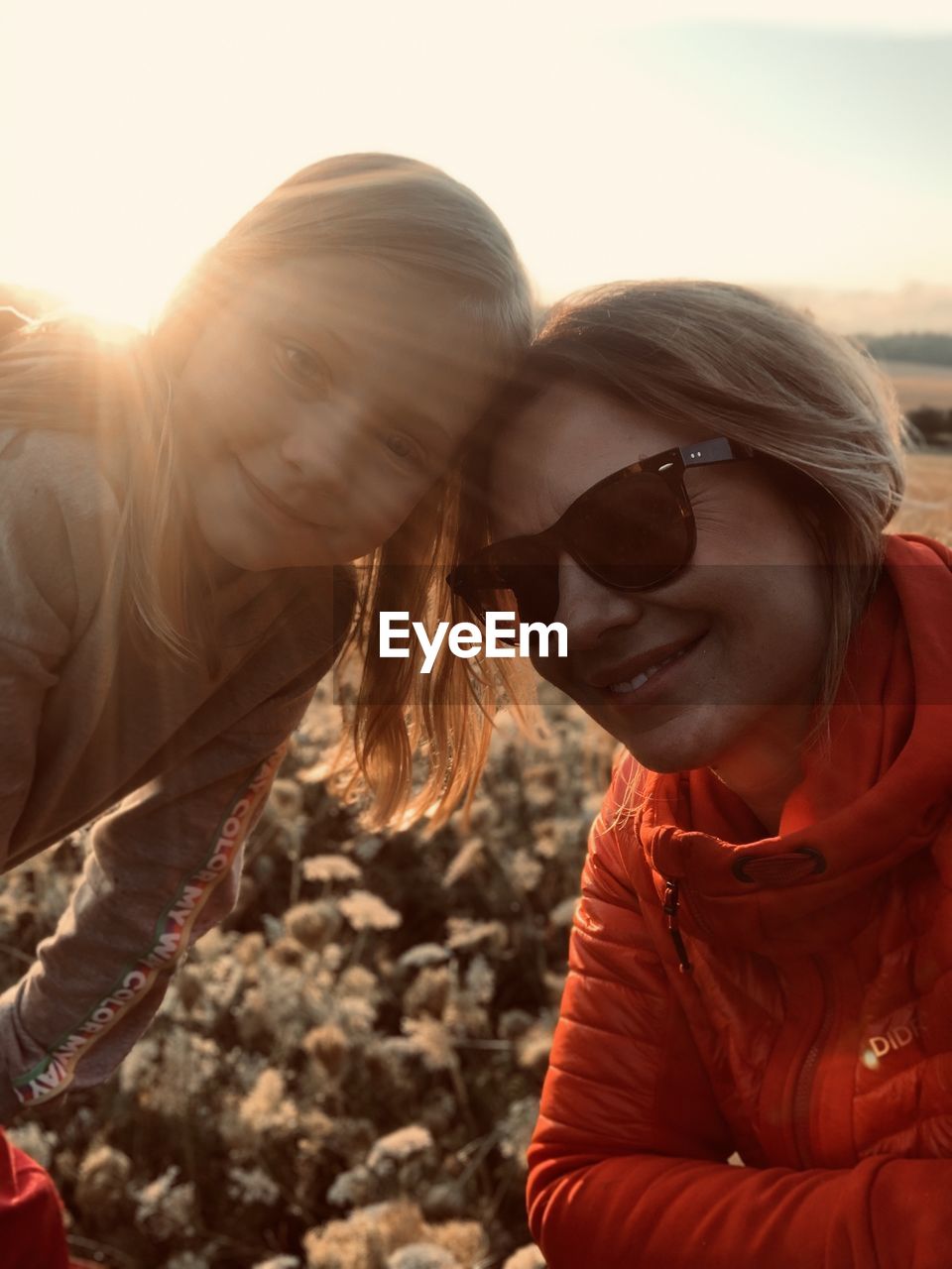 PORTRAIT OF SMILING YOUNG WOMAN WITH SUNGLASSES AGAINST SKY