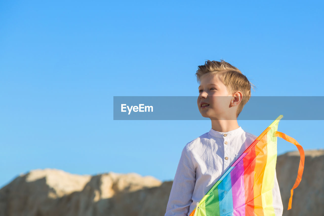 A boy with a kite stands mountain and looks into the distance. the concept of freedom and fantasy.