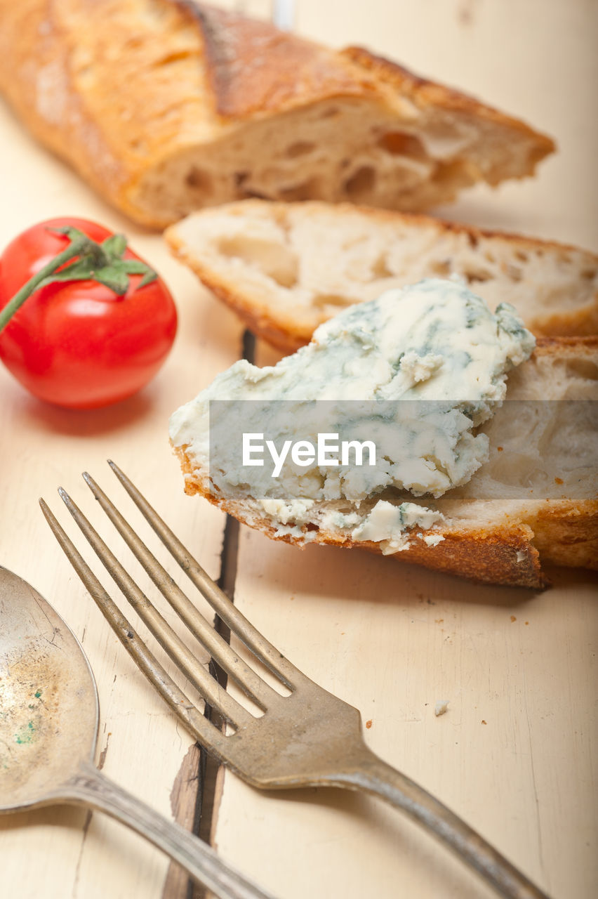 High angle view of bread with cheese by tomato on wooden table