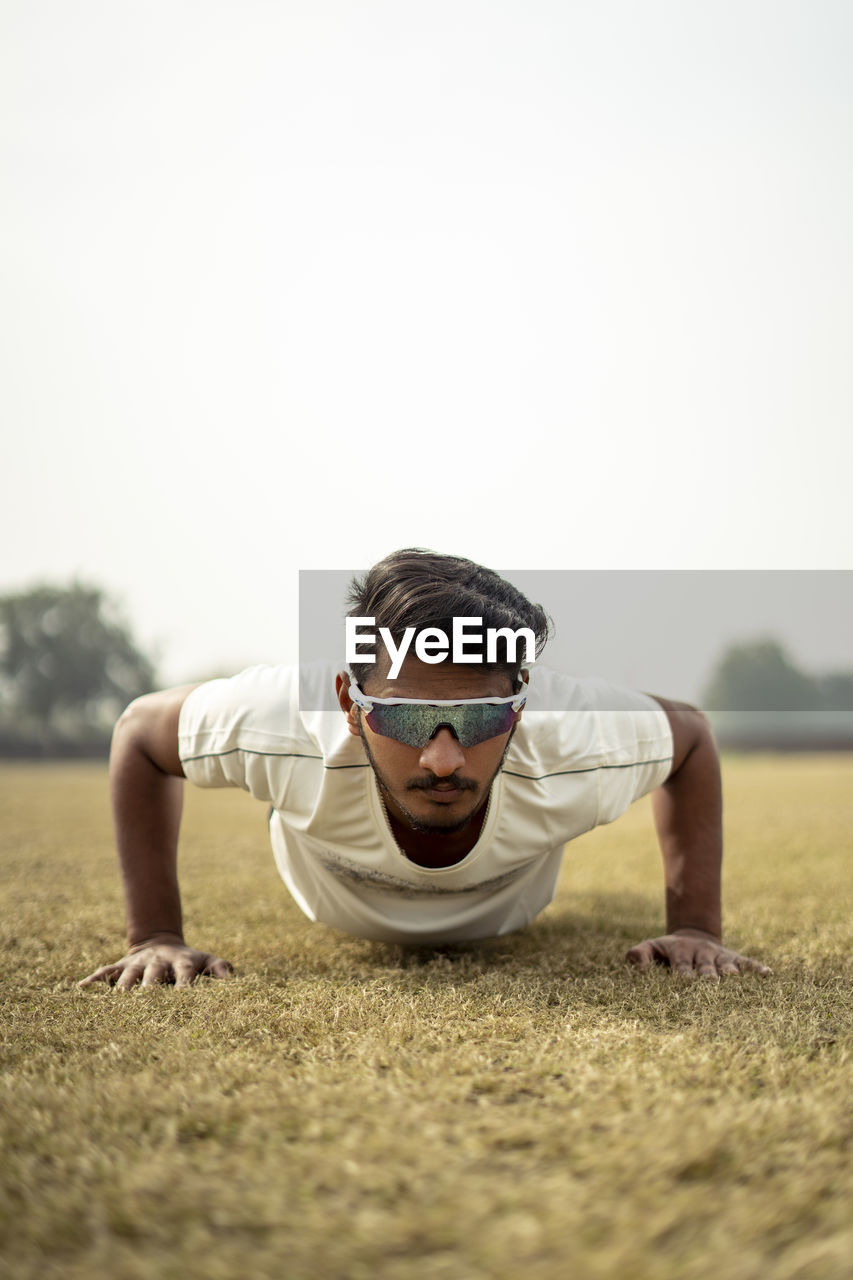 Close up portrait of a young indian sportsman exercising in the field. sportsman doing push ups