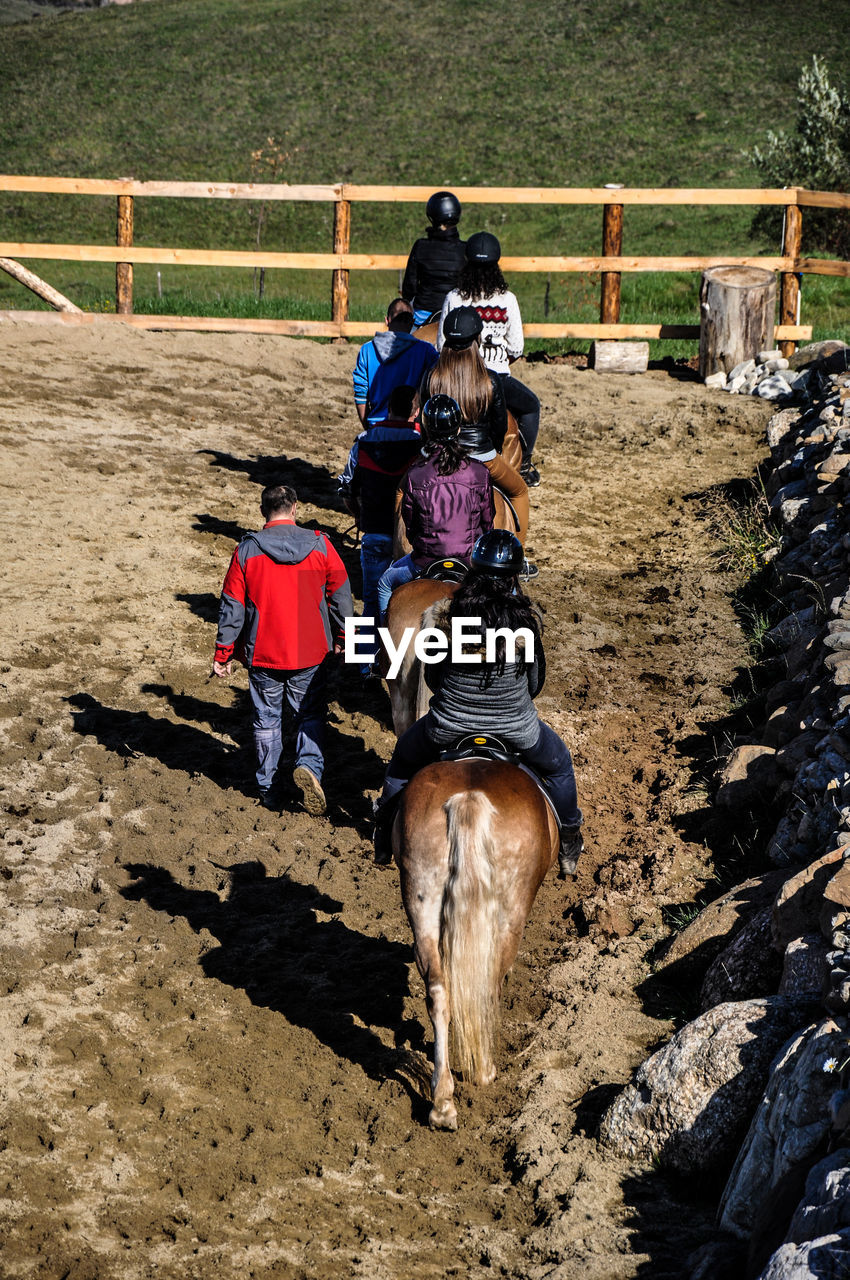 High angle view of people sitting on horseback in fenced rural ranch