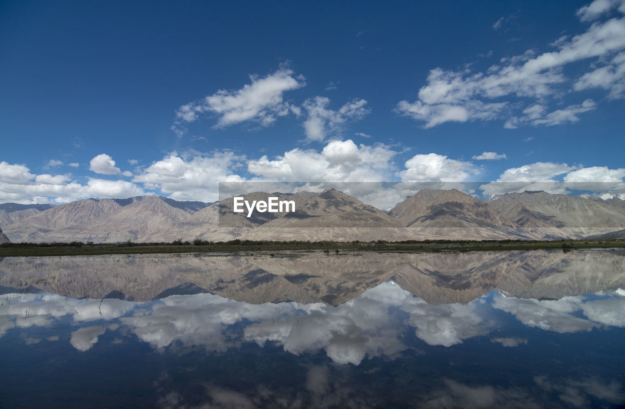 Scenic view of lake and mountains against blue sky