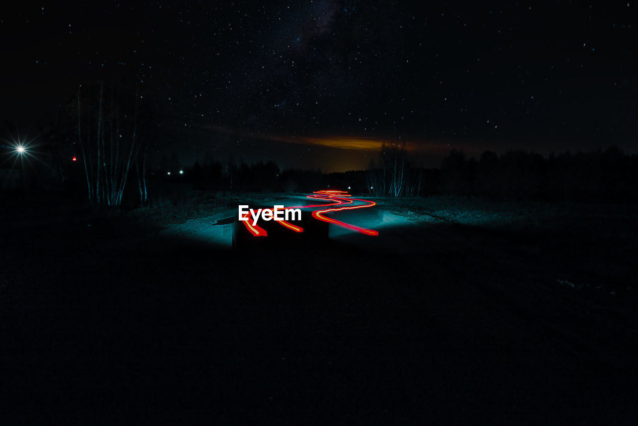 Light trails on road against sky at night