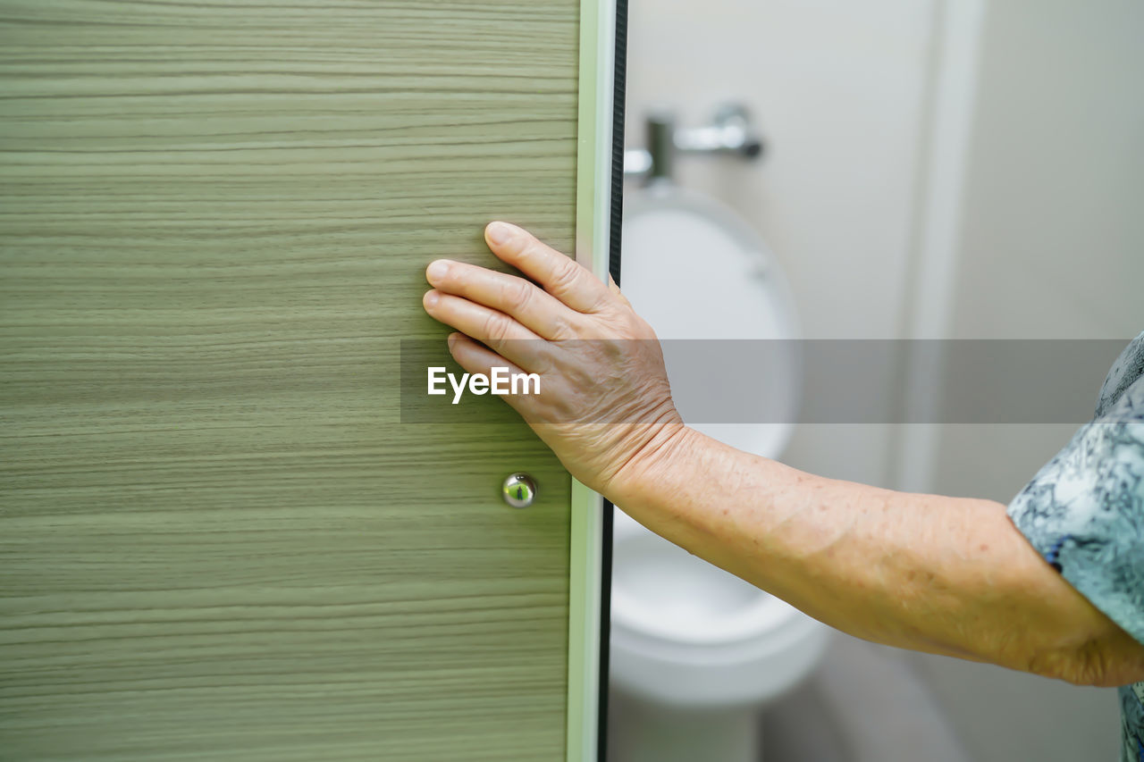 Cropped hand of woman entering bathroom at home