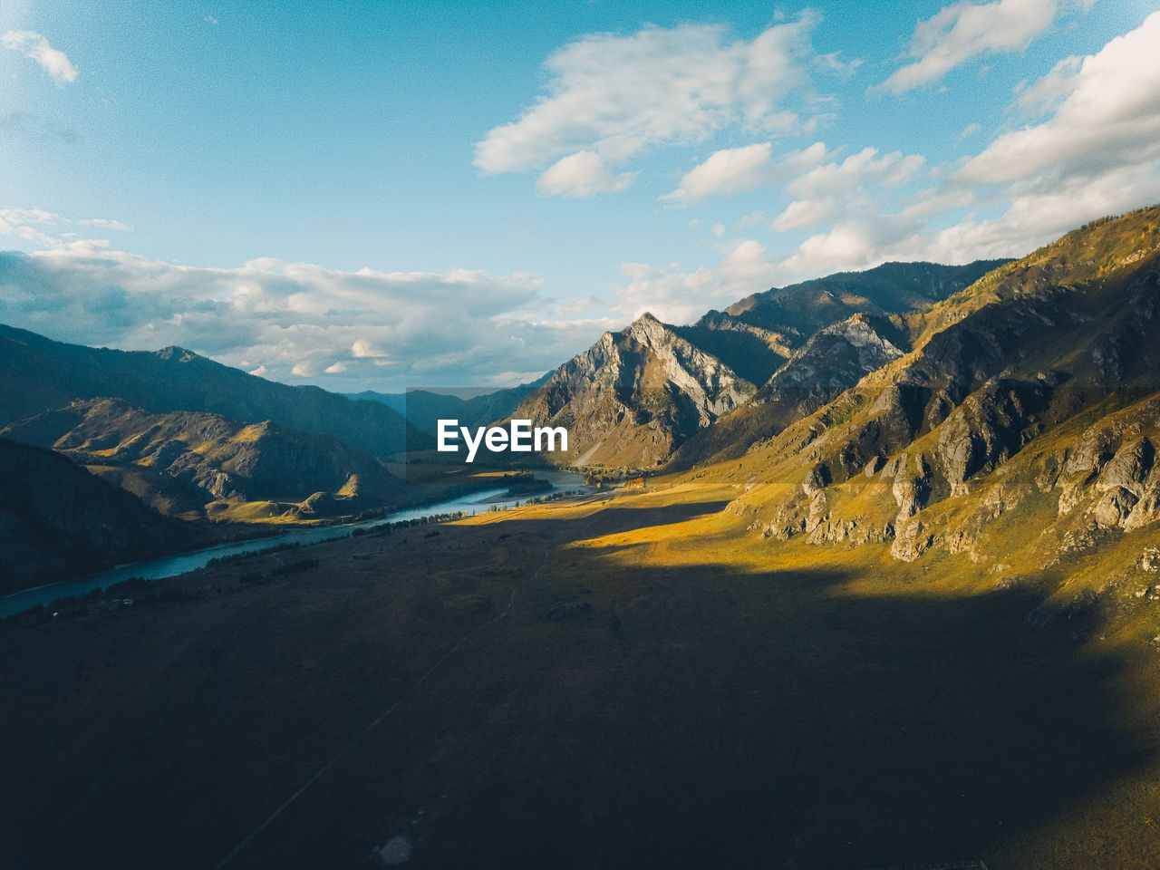 Bright yellow textured mountains against a blue sky, aerial view. sunset. drone shot