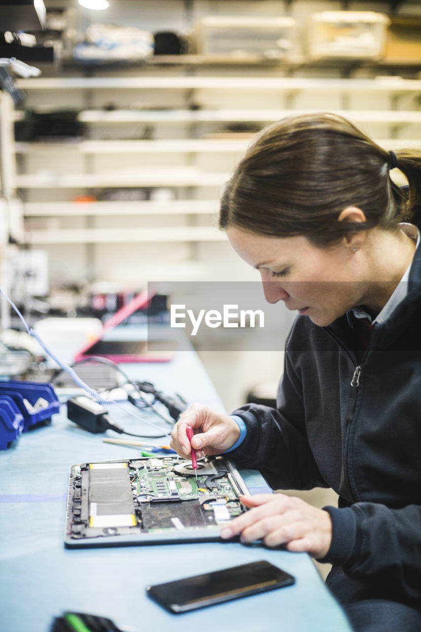 Female engineer repairing computer equipment in workshop