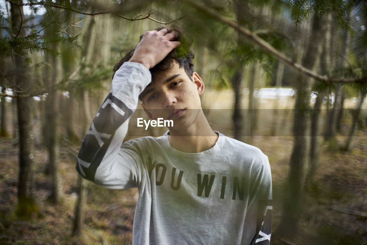 Portrait of young man standing at forest