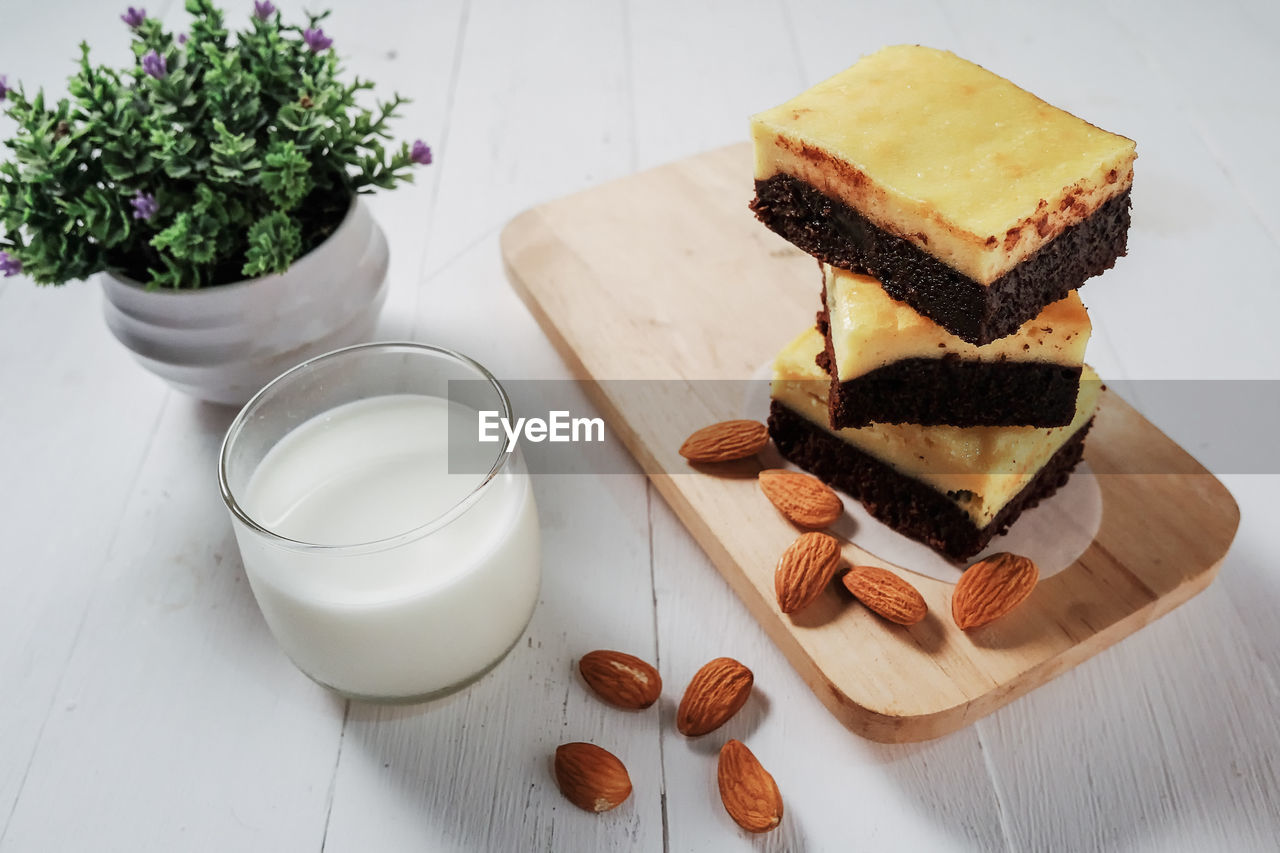 Cream cheese brownies with almond and milk on white wooden.close up