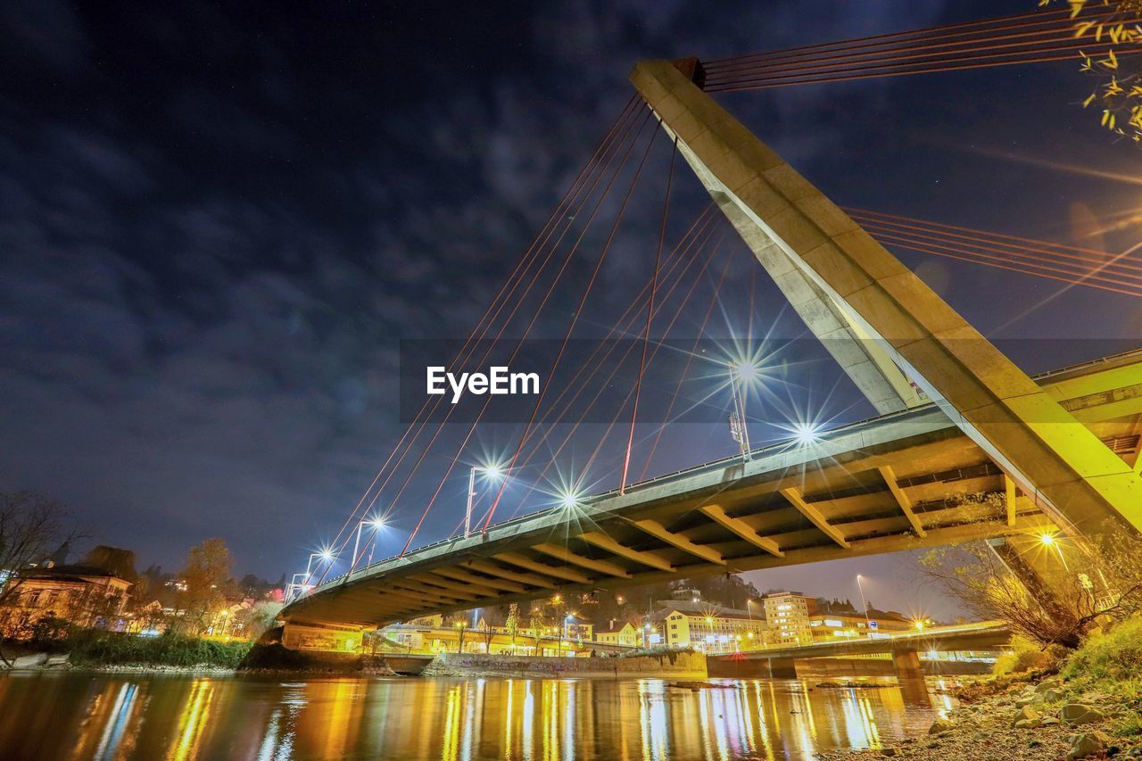 Low angle view of illuminated bridge over river at night