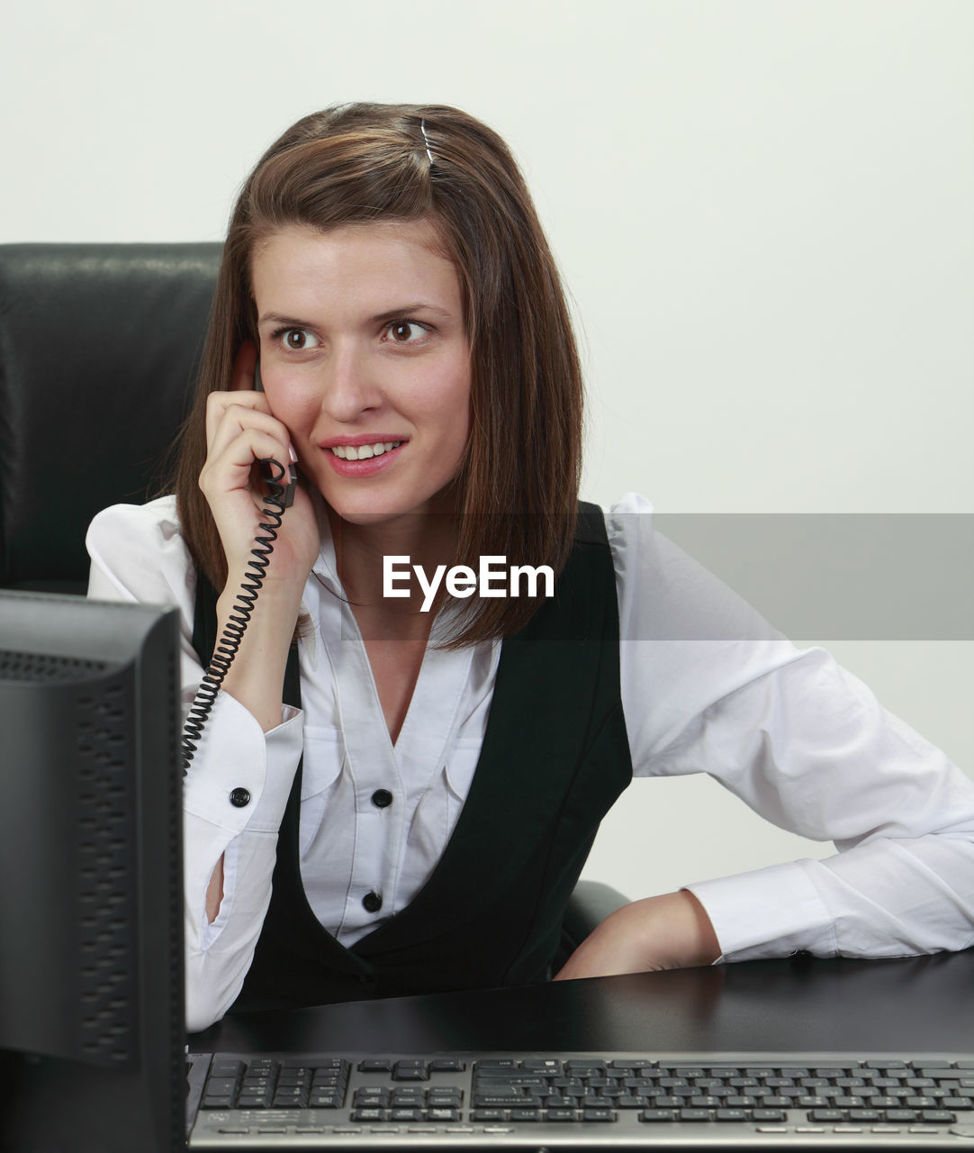 Smiling young businesswoman talking on telephone over white background