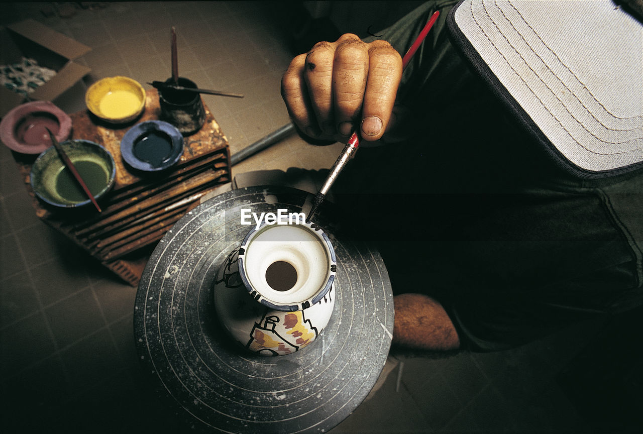 High angle view of man painting over earthenware