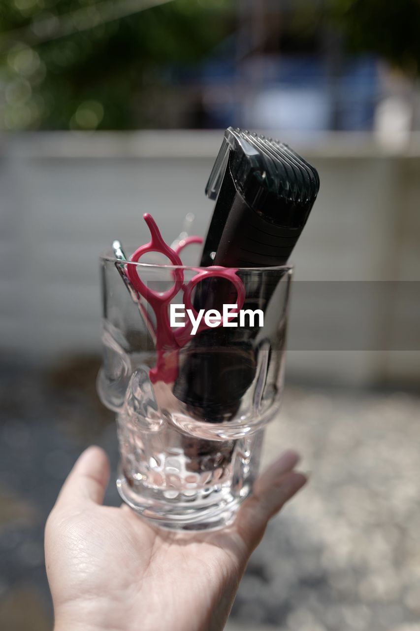 CLOSE-UP OF HAND HOLDING GLASS OF DRINK