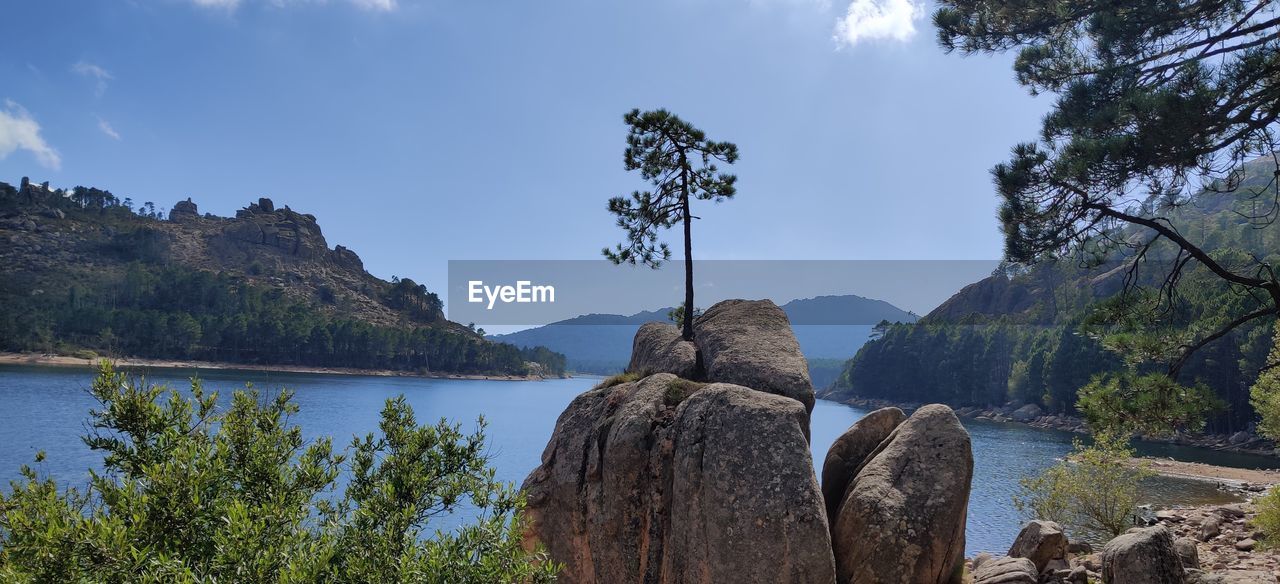 Panoramic view of rocks by lake against sky