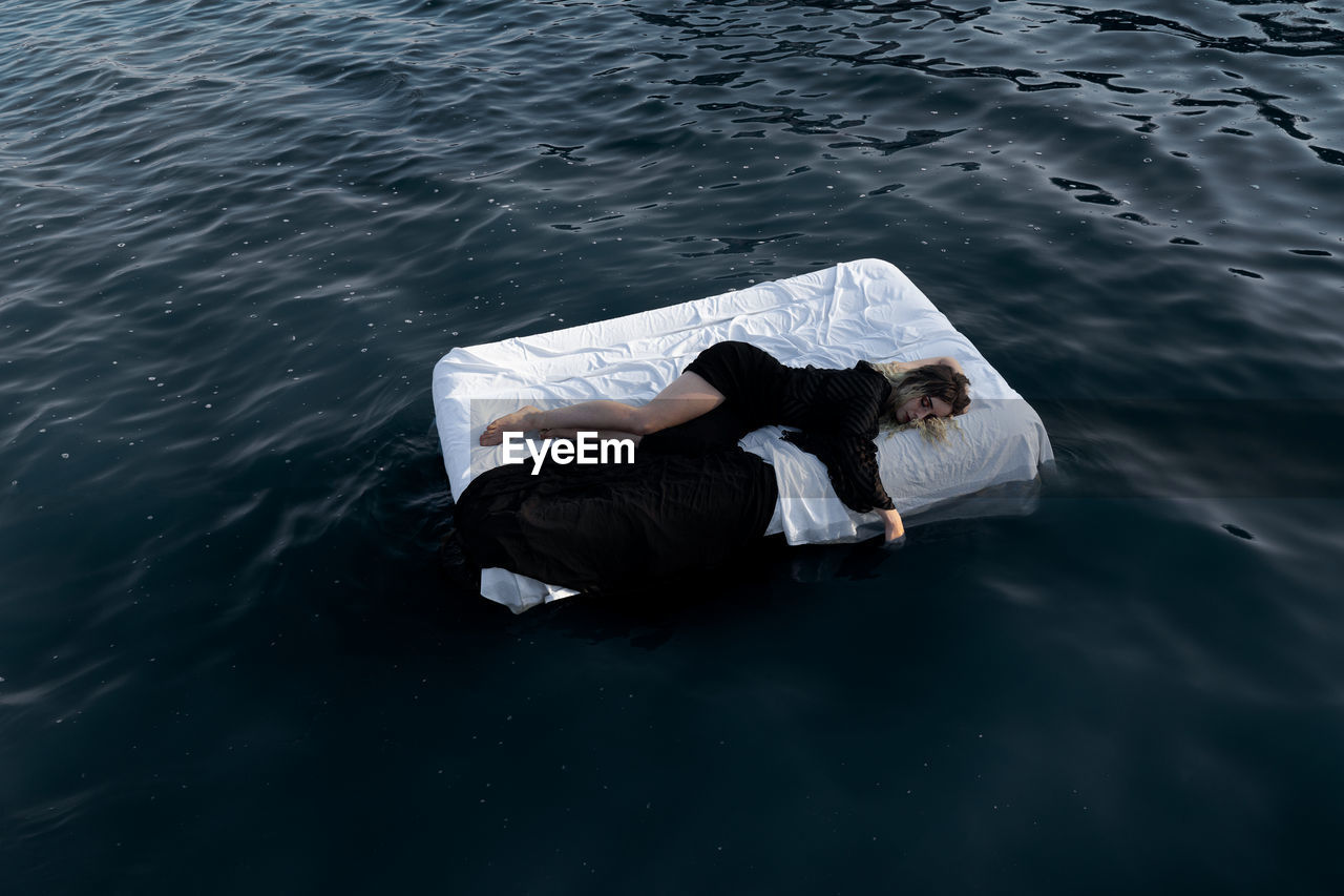 High angle view of young woman sleeping on bed floating in lake