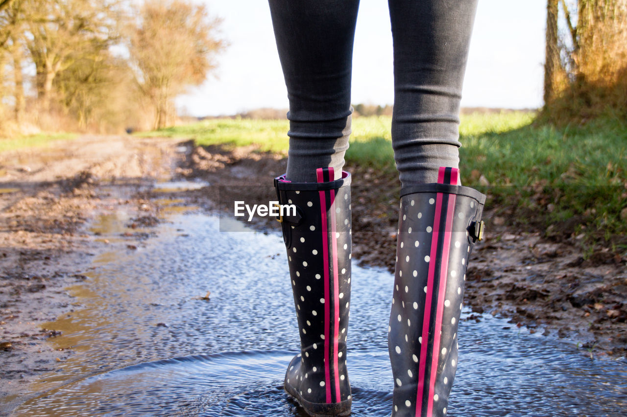 Low section of woman walking on dirt road