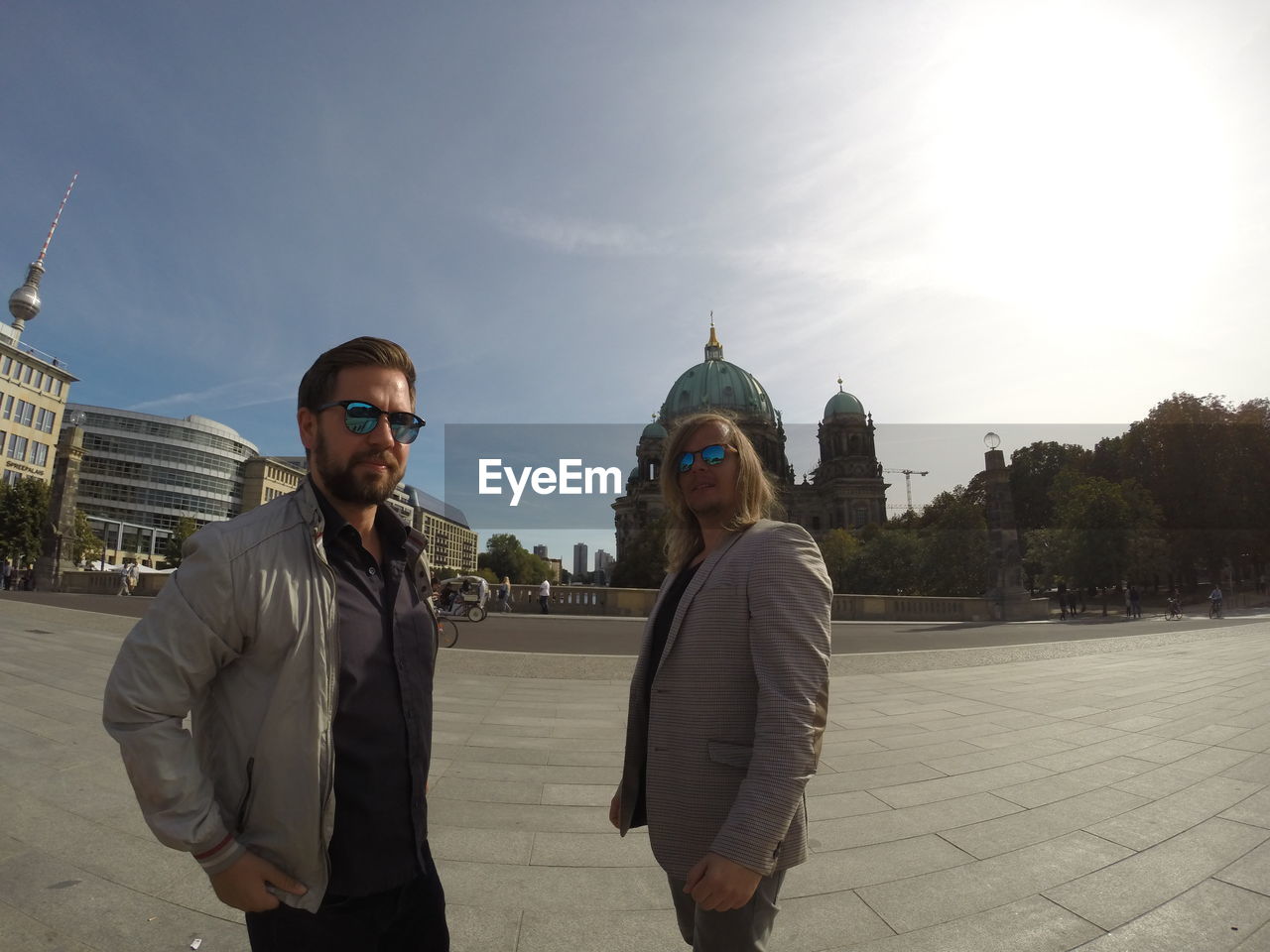 Male friends standing on street against berlin cathedral in city