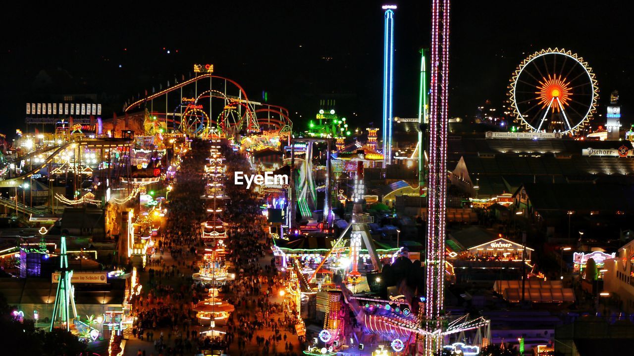 ILLUMINATED AMUSEMENT PARK RIDE AGAINST SKY AT NIGHT