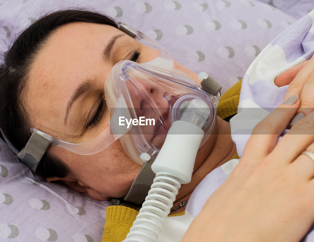 Close-up of female patient with oxygen mask sleeping on bed