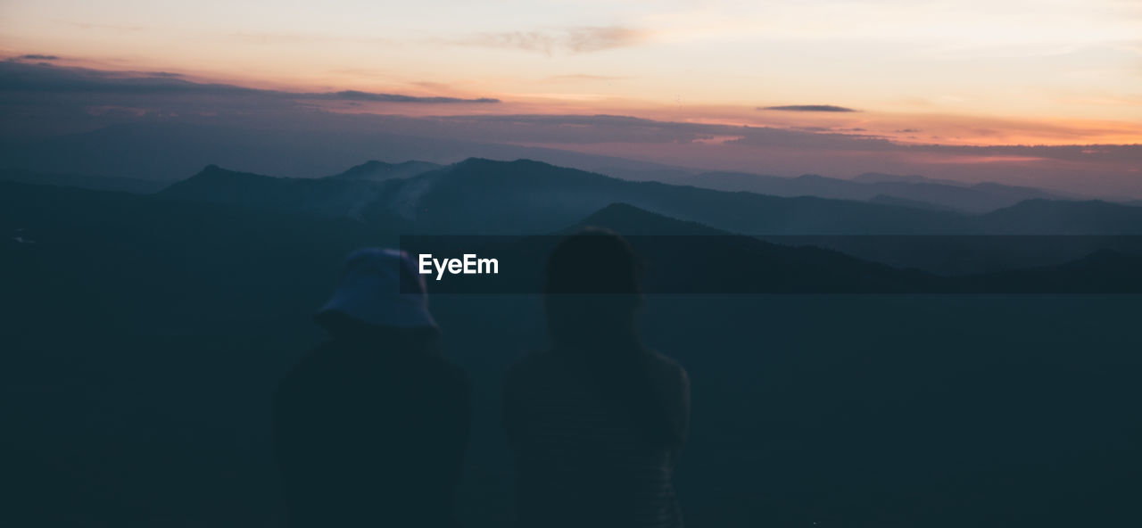 Silhouette people on mountains against sky during sunset