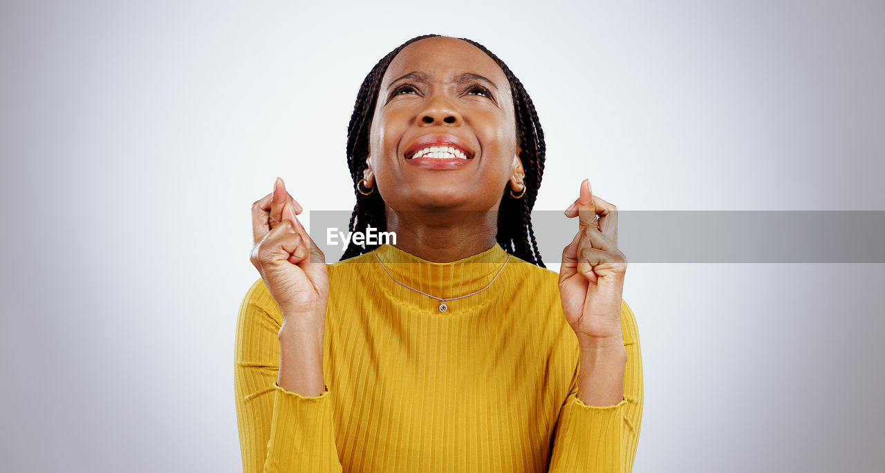 studio shot, yellow, one person, adult, women, smiling, happiness, portrait, indoors, emotion, cheerful, front view, waist up, person, young adult, gesturing, female, clothing, copy space, standing, positive emotion, gray background, looking, looking up, human face, finger, hand, casual clothing, smile, photo shoot, teeth, gray, white background, hairstyle, eyes closed, arm