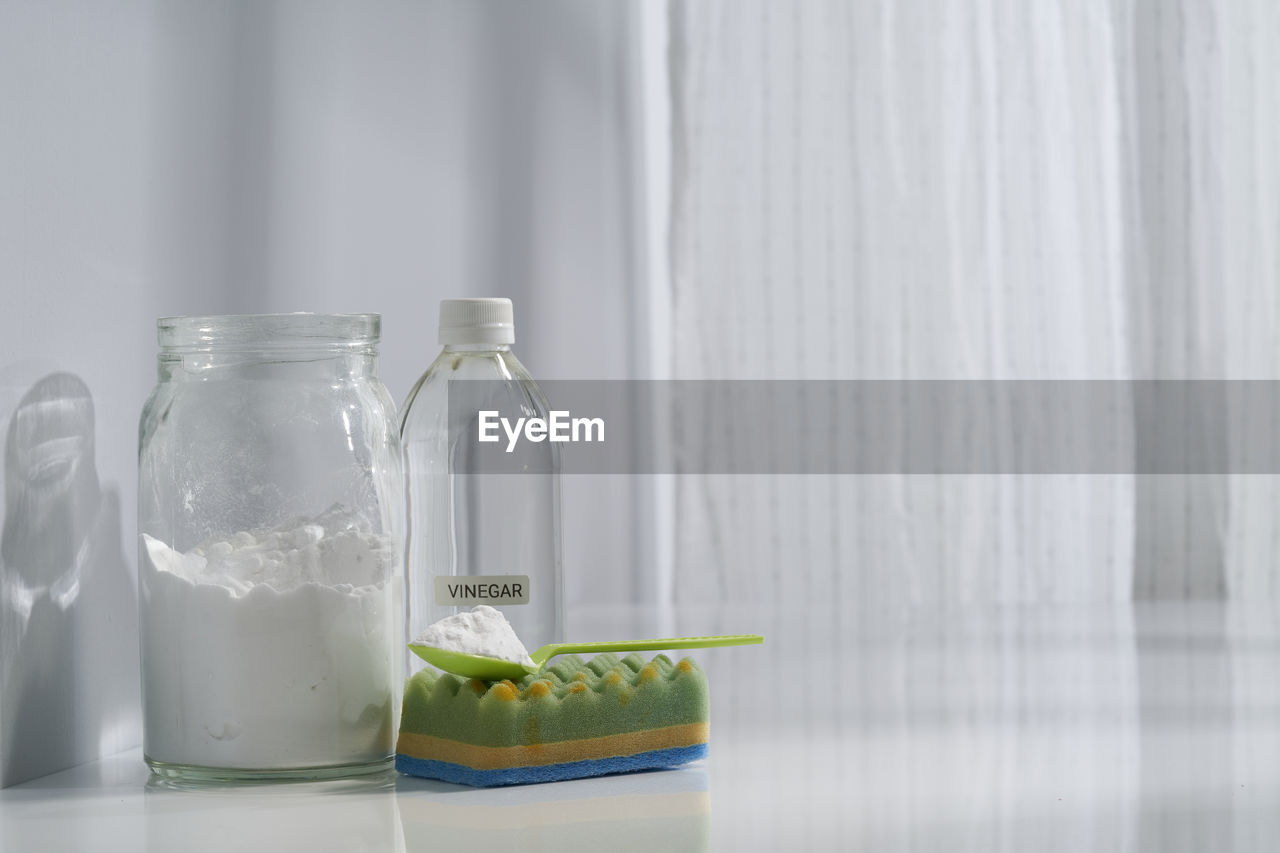 Jar of baking soda , white vinegar and cleaning sponge