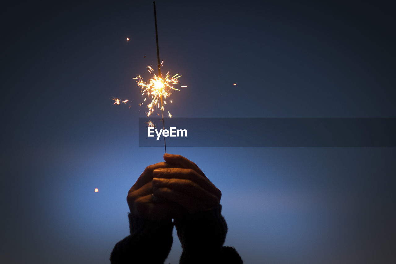 Person holding sparkler at night