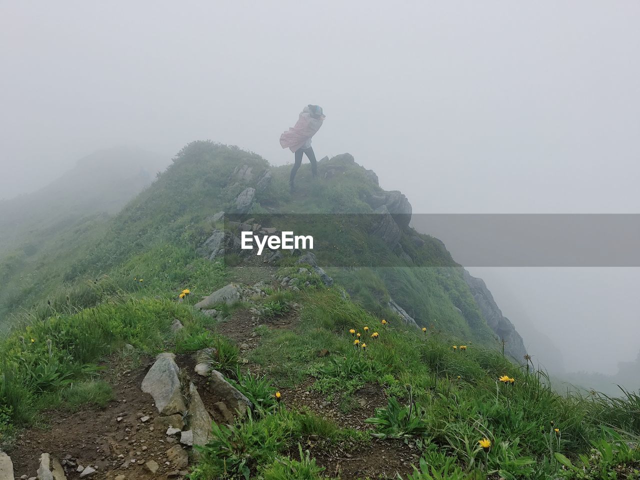 Female hiker standing on mountain against sky during foggy weather