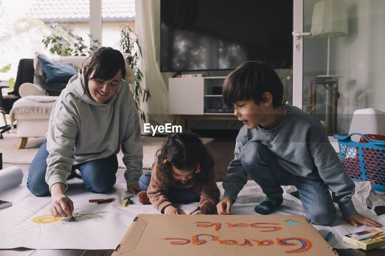 Mother drawing with son and daughter in living room at home