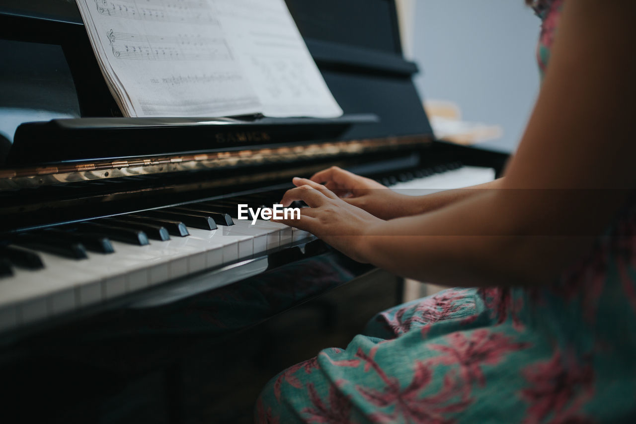 Midsection of girl wearing dress while playing piano