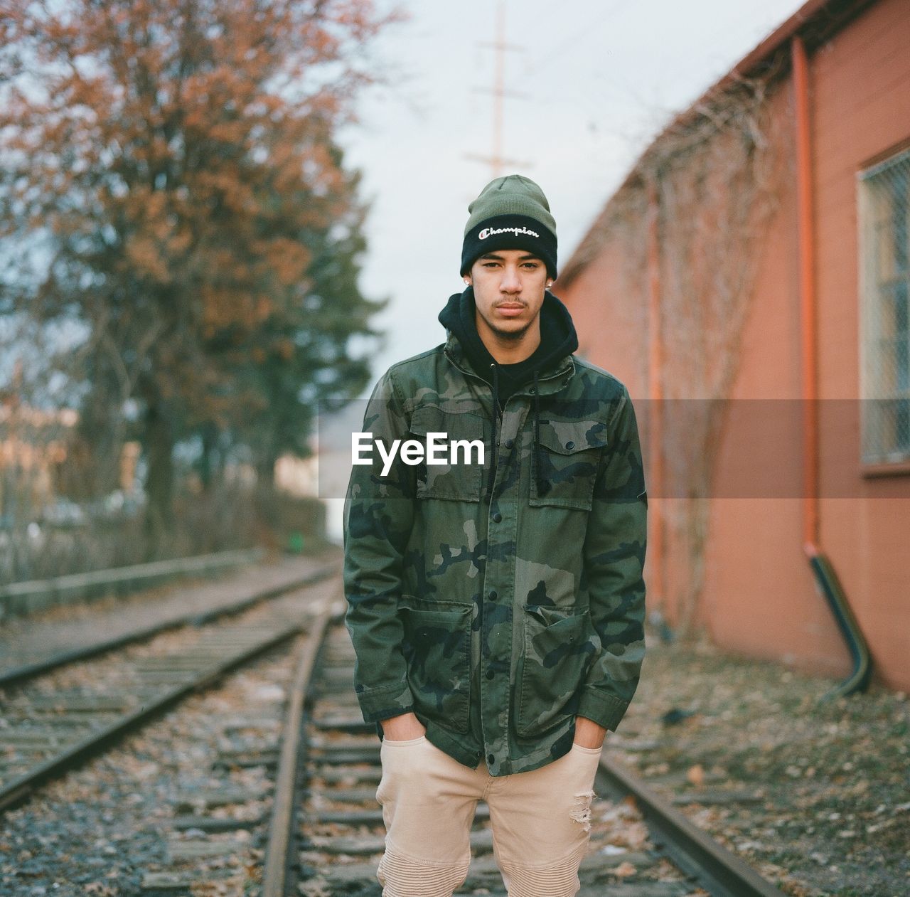 PORTRAIT OF MAN STANDING BY RAILROAD TRACK