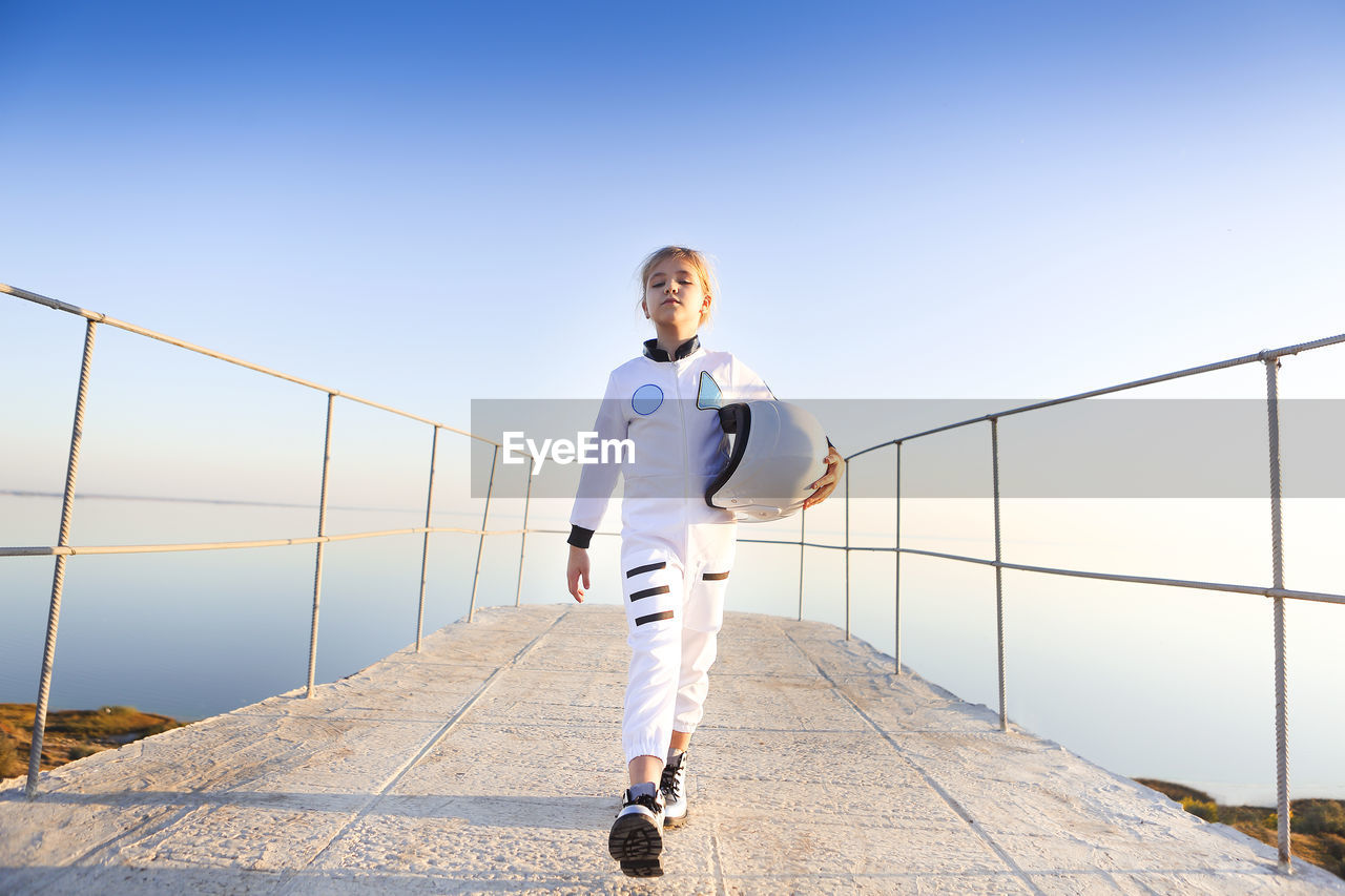 Portrait of girl walking on observation point against railing and clear sky