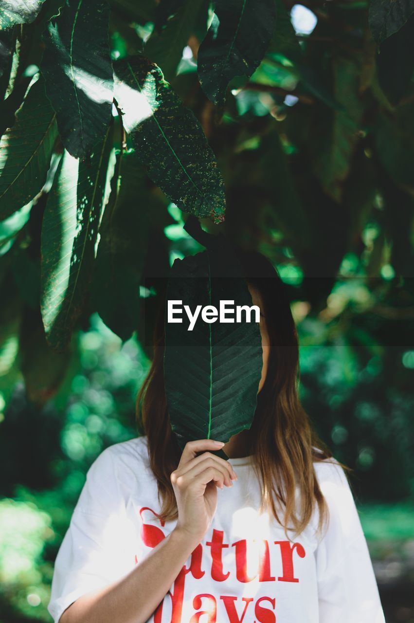 Woman holding leaf over face