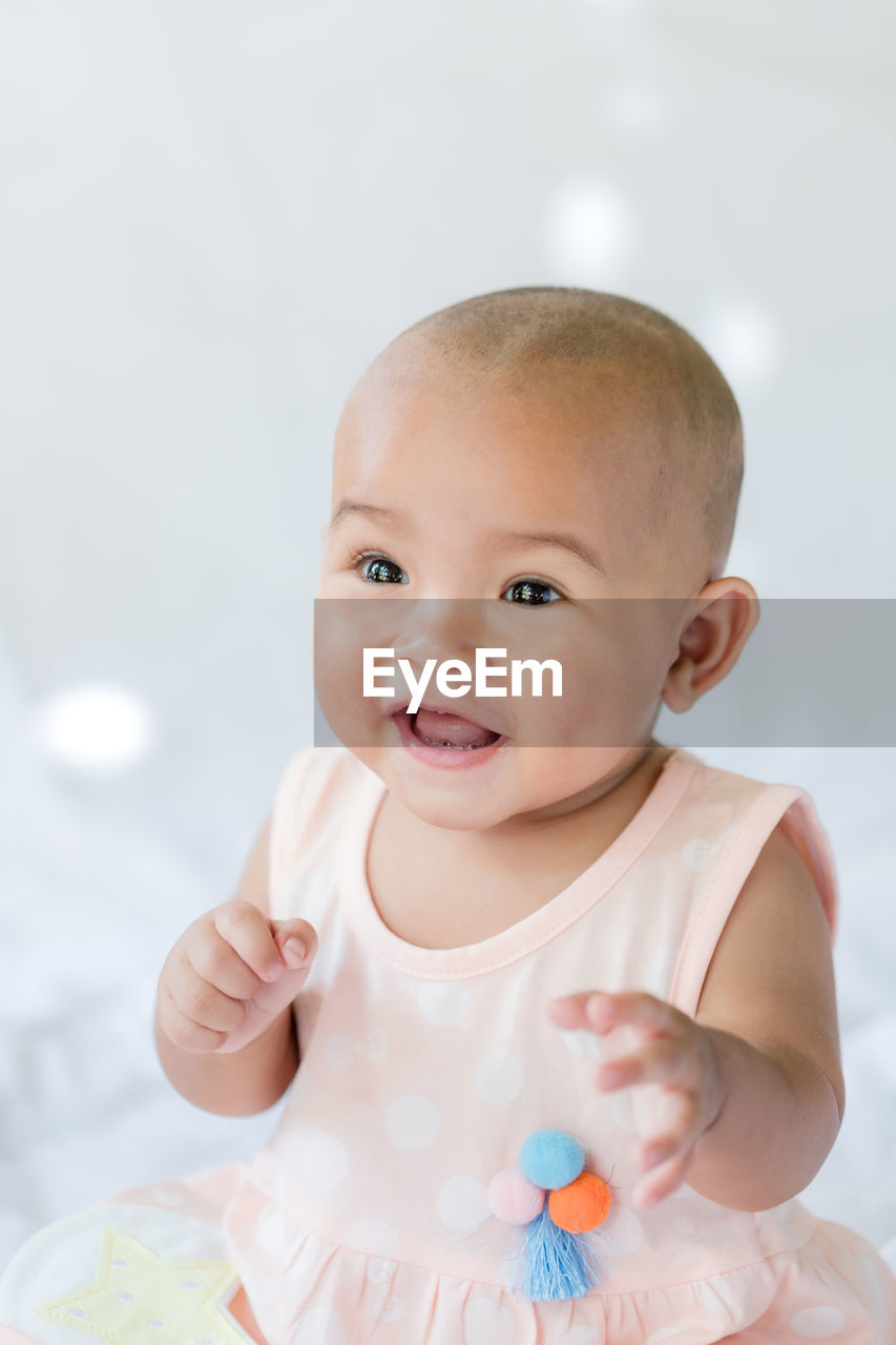 Cute baby girl sitting on bed