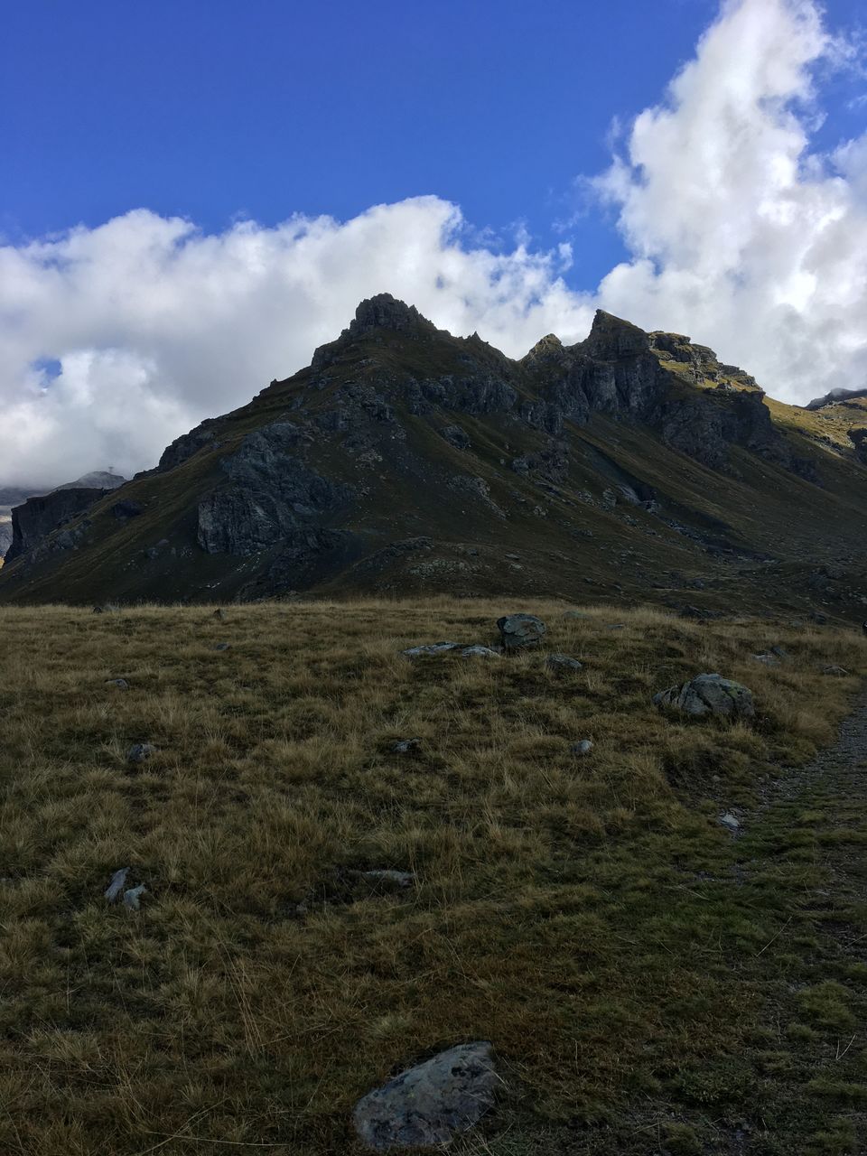 cloud, sky, nature, blue, mountain, rock, adventure, day, beauty in nature, low angle view, scenics - nature, cliff, outdoors, no people, mountain range, rock formation, environment, terrain, land, tranquility, ridge, geology, landscape, non-urban scene, travel, travel destinations