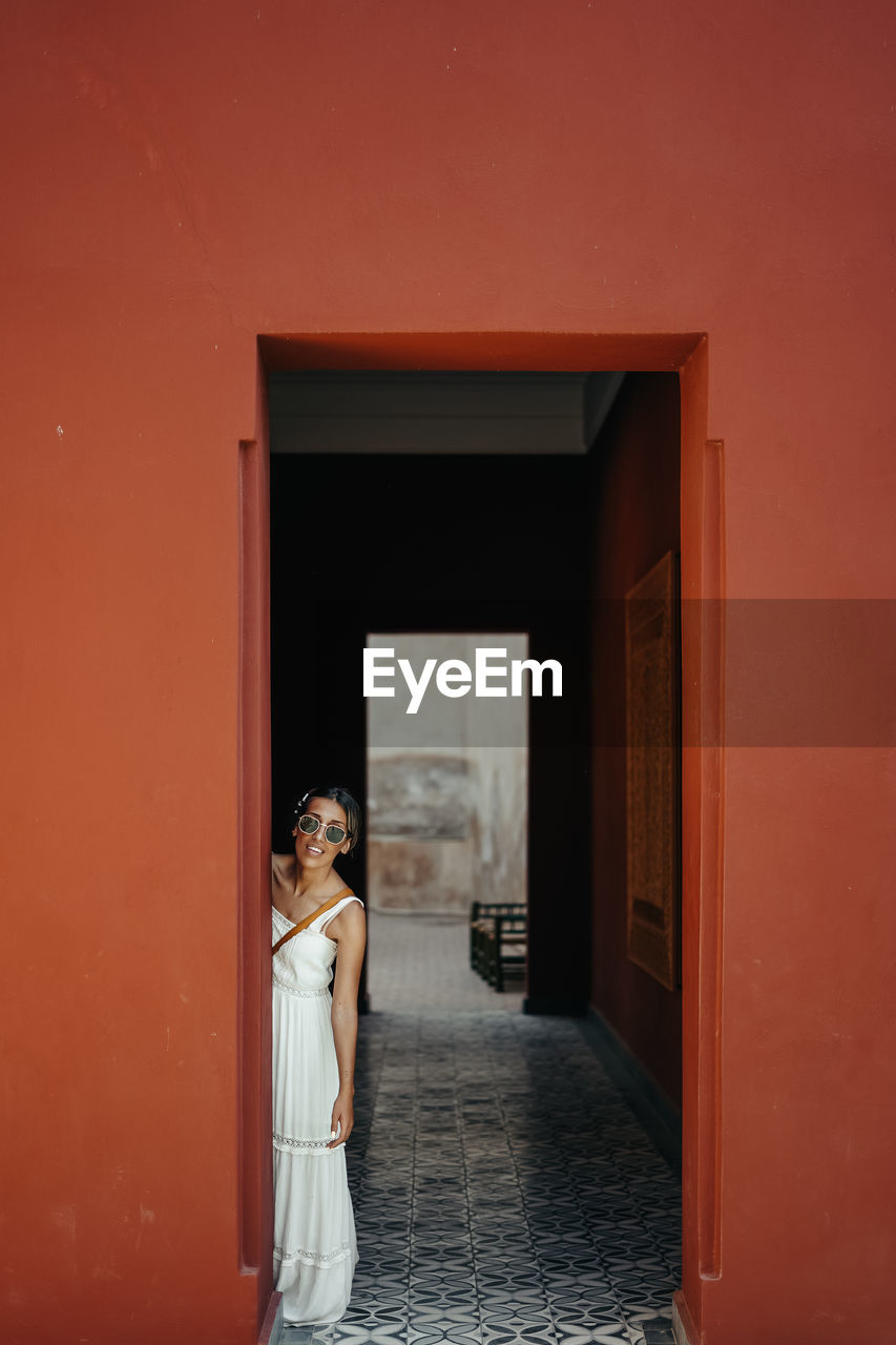 Woman wearing sunglasses standing by doorway