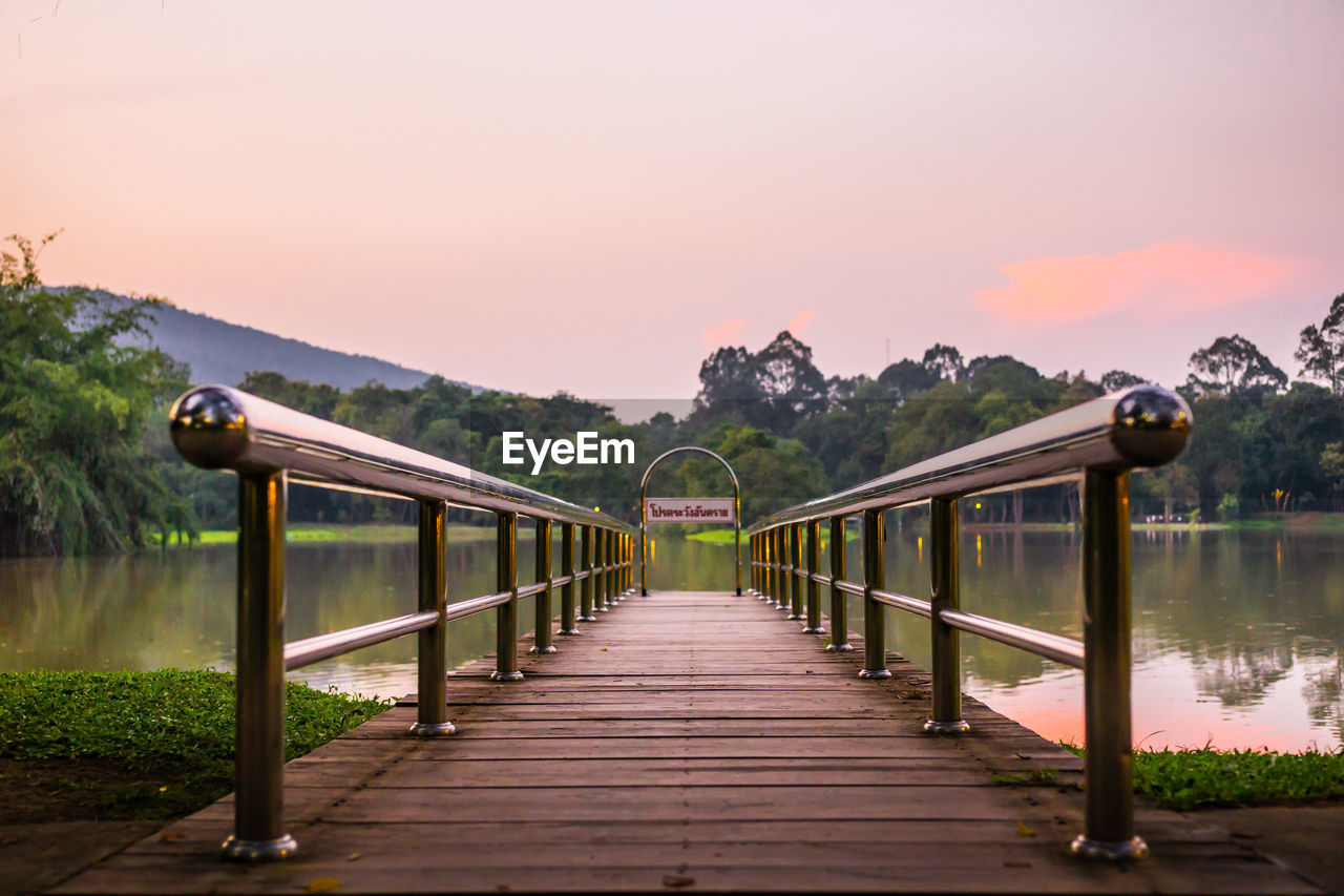 BRIDGE OVER CALM LAKE AGAINST SKY