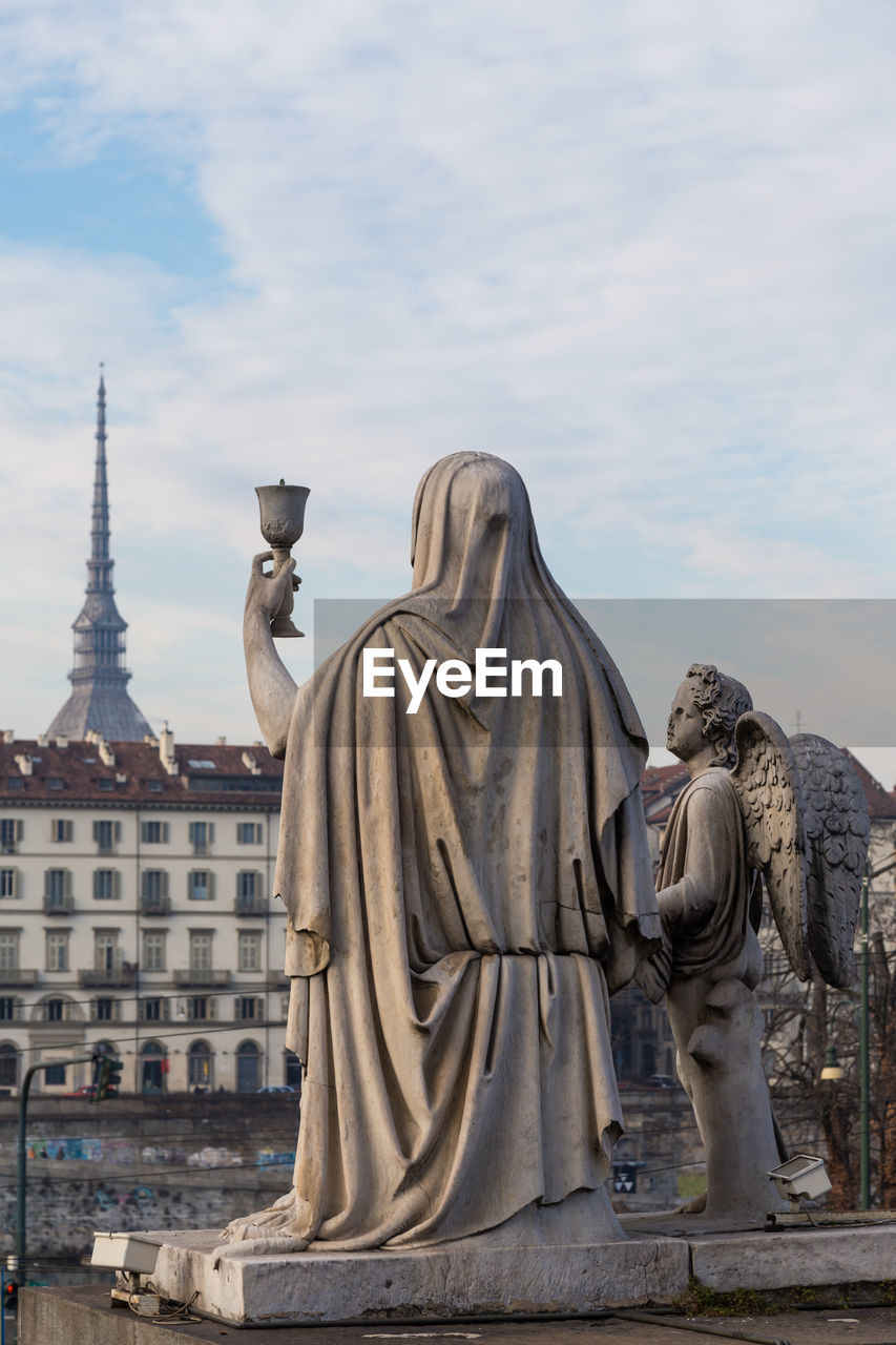 Statue in front of buildings at piazza vittorio veneto against sky