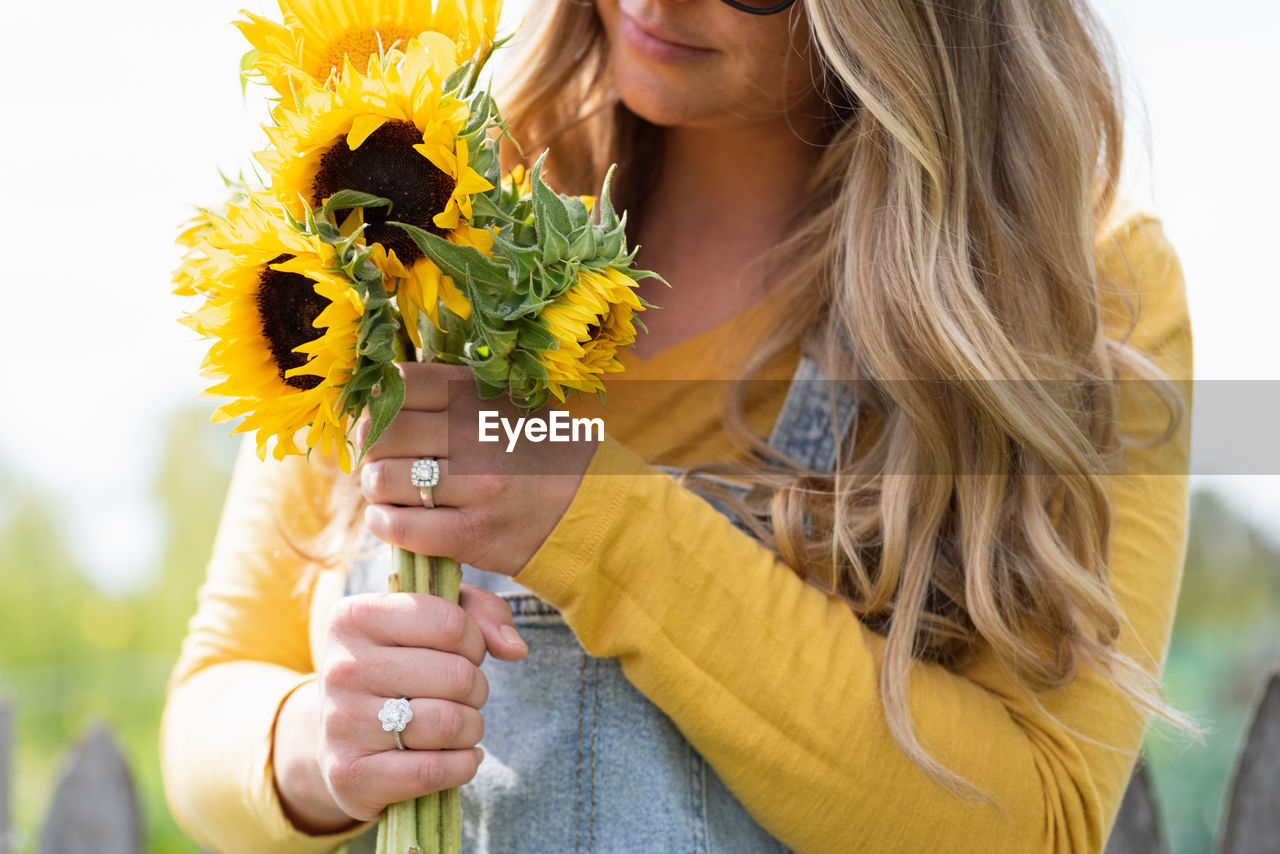 Midsection of woman holding flower bouquet outdoors