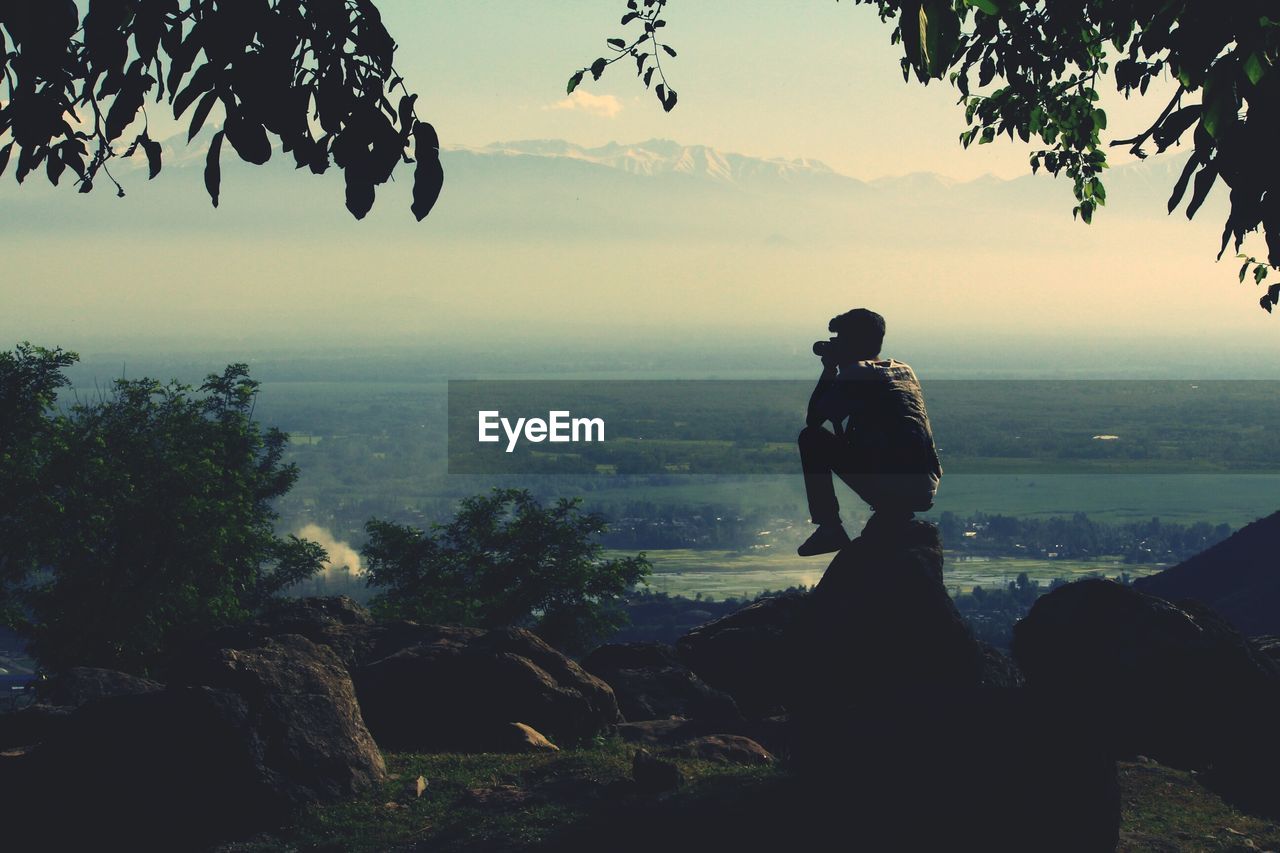 Silhouette of man photographing landscape