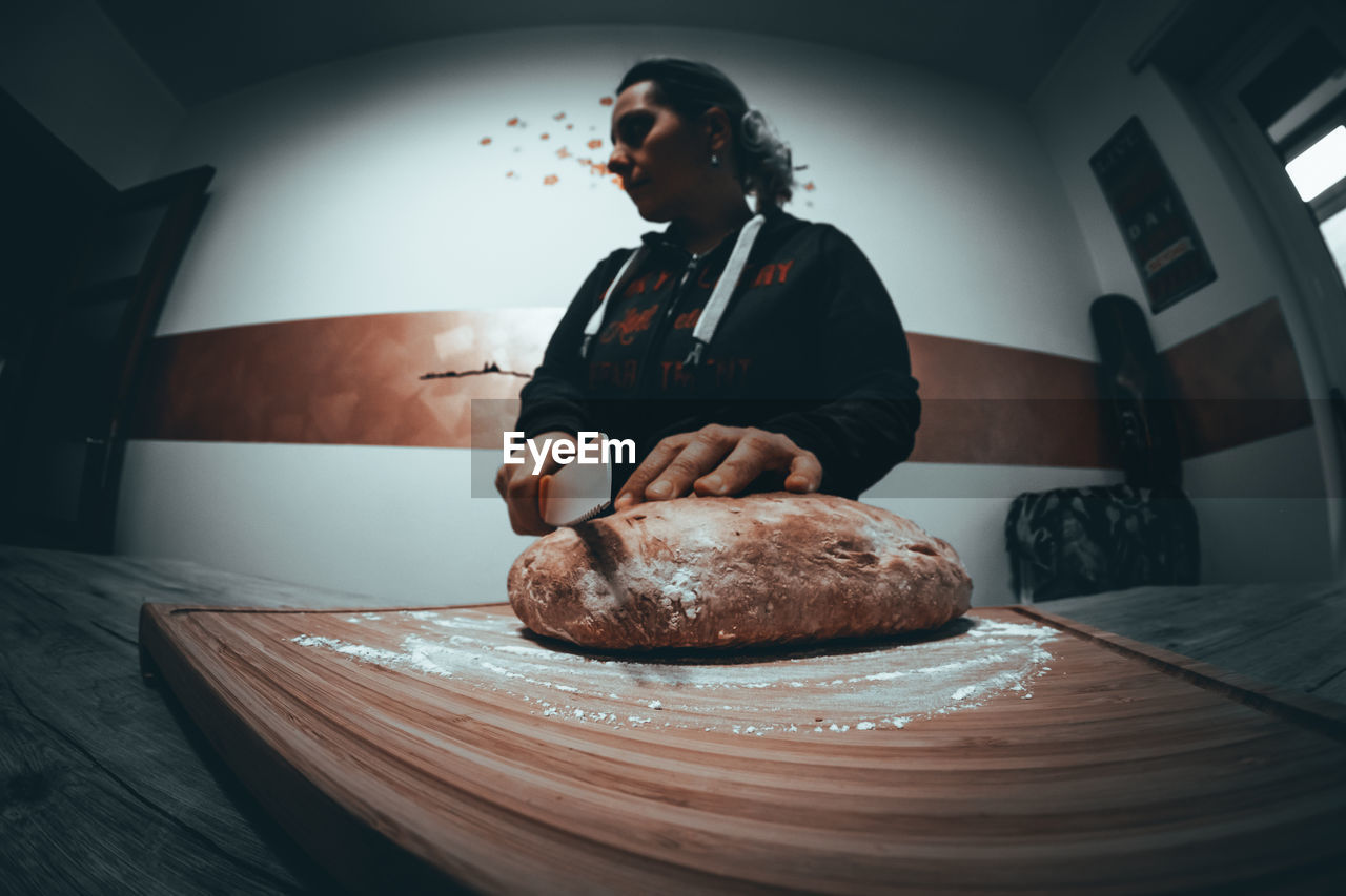 Low angle view of woman cutting bread on table at home