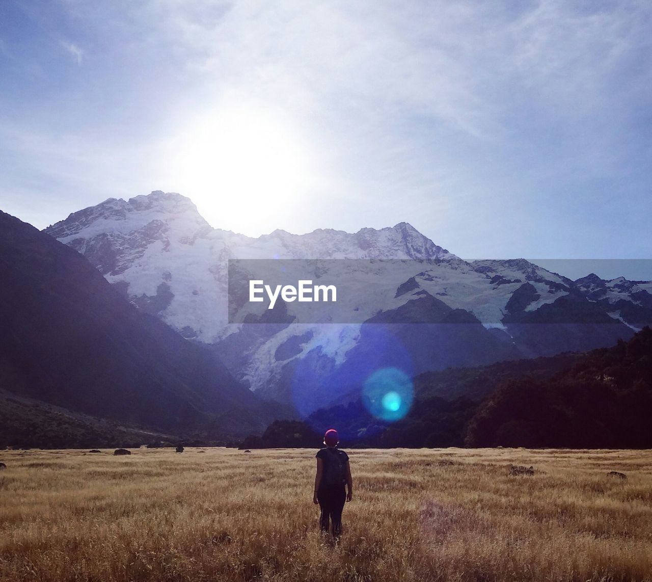 Rear view of woman walking against mountains at mt cook national park during sunny day