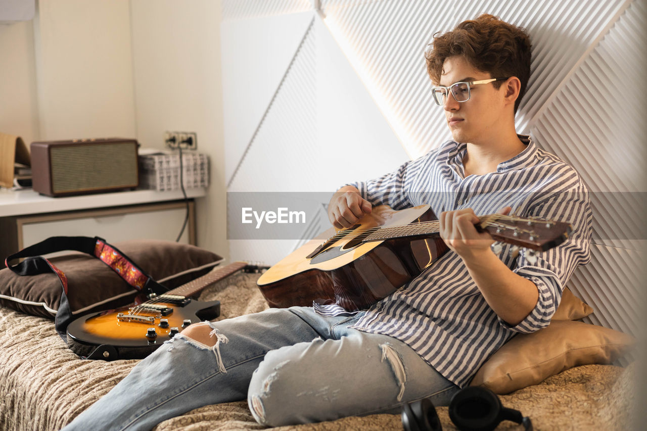 young man using mobile phone while sitting on sofa at home