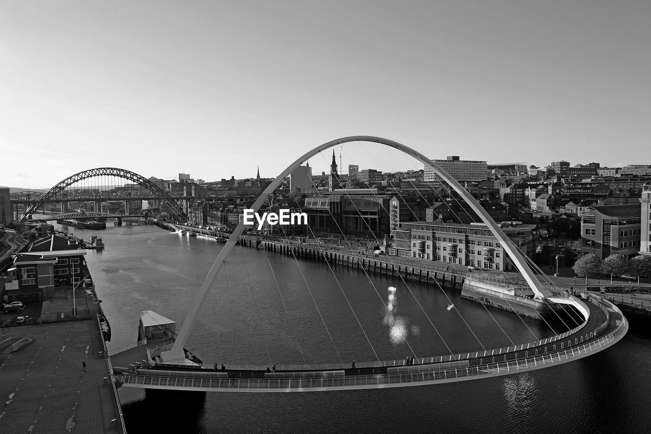 Bridge over river in city against clear sky