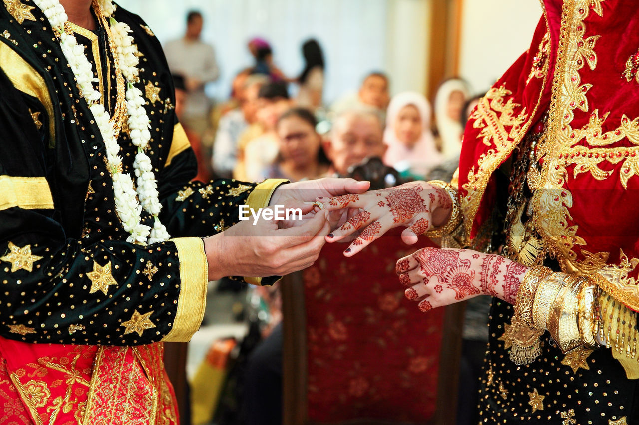 Asian muslim couple holding and putting ring each other hand in minangkabau wedding ceremony.