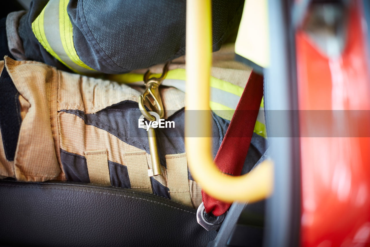 Midsection of firefighter with key ring sitting in fire truck
