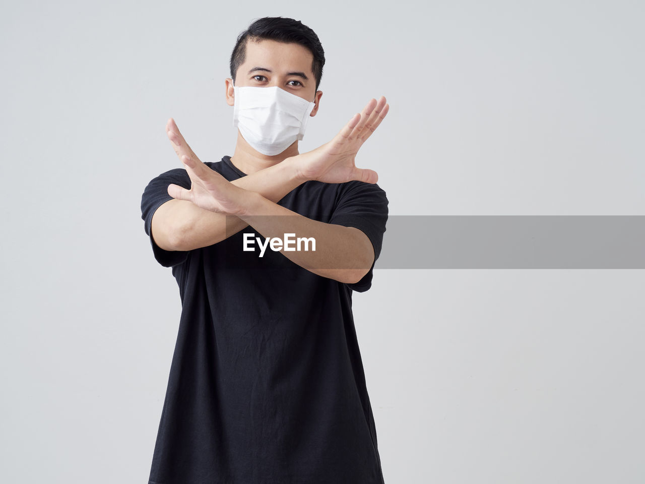 Portrait of man wearing mask gesturing while standing against white background