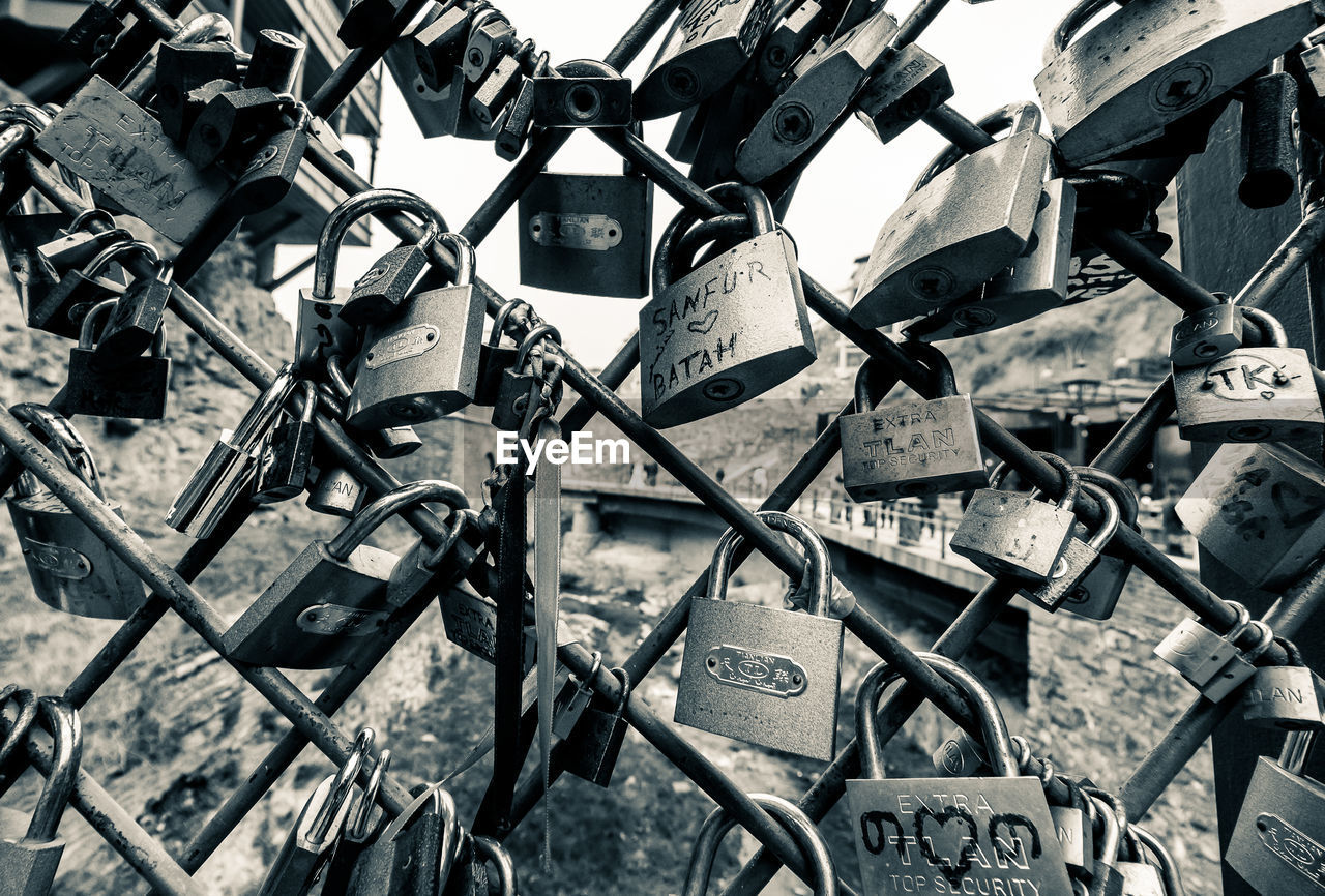 Close-up of padlocks on chainlink fence at bridge