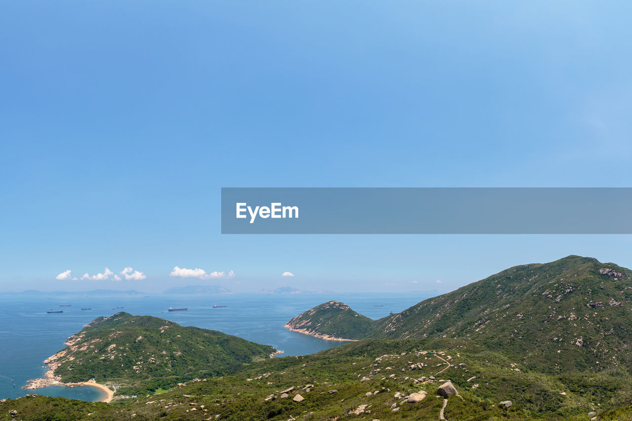 Scenic view of sea and mountains against blue sky