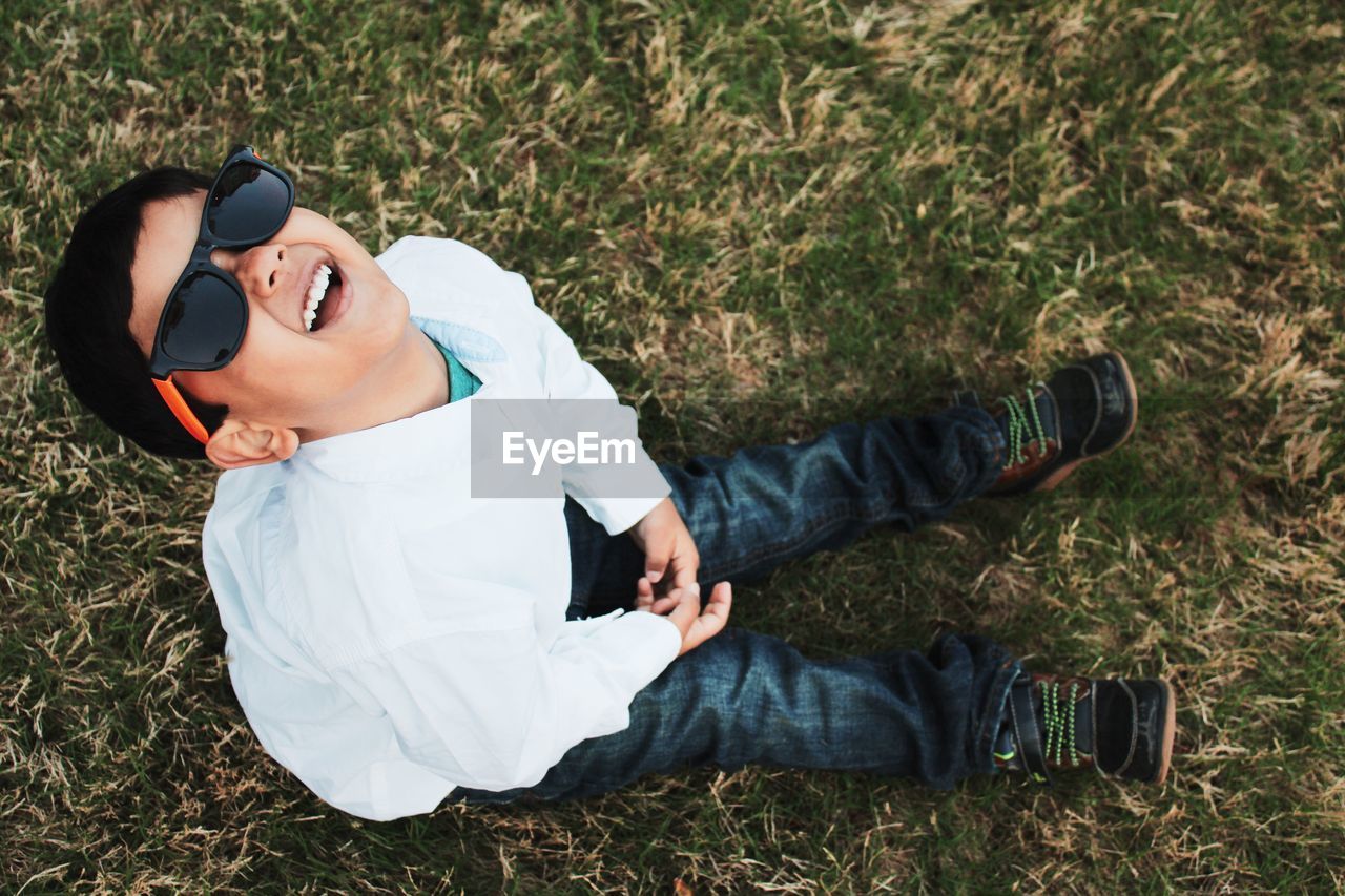 High angle view of happy boy sitting on field