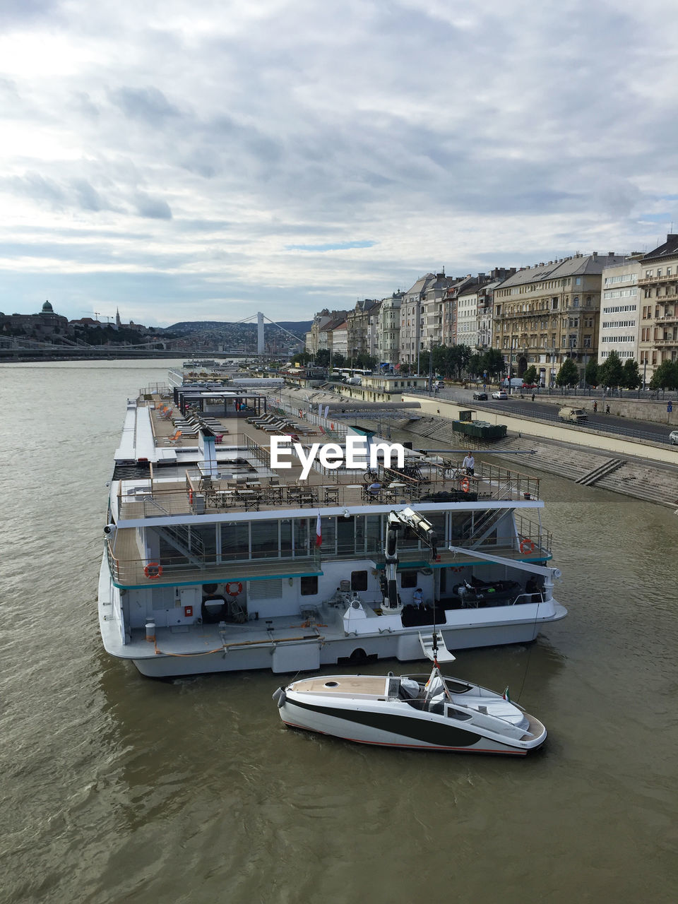 BOATS MOORED IN SEA WITH CITY IN BACKGROUND